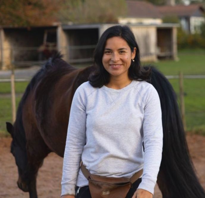 Alexandra de face avec un cheval derrière, ravi de son accompagnement cavalier cheval